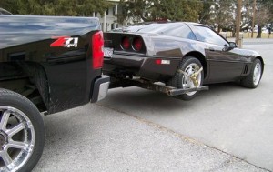 Pick up truck tows car using a automatic wheel lift system.