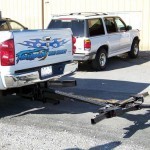 An automatic wheel lift attached to a pickup truck for towing cars.